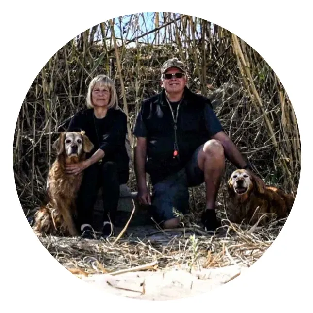 A couple kneeling with their golden retrievers